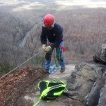 Kevin checks his rappelling gear before going over the cliff.